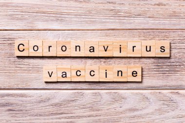 Koronavirüs aşısı kelimesi tahta blokta yazılı. Coronavirus aşısı metni ahşap masa üzerinde sizin desing, konsept üst görünüm için