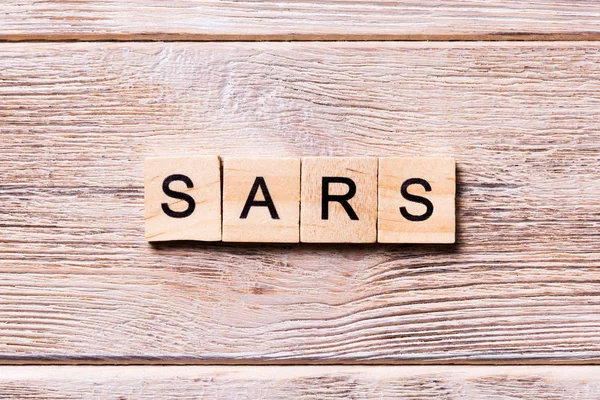Kata SARS ditulis di balok kayu. Teks SARS di atas meja kayu untuk tampilan atas konsep desing dan koronavirus — Stok Foto