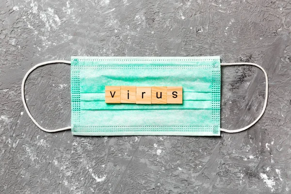 virus word written on wood block lying on medical mask. virus text on gray table for your desing, coronavirus concept top view