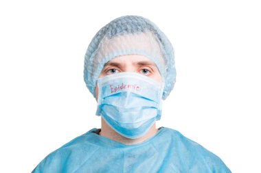 Sağlık üniforması giyen genç bir adamın portresi ve beyaz arka planda salgın sözcüğü olan koruyucu bir maske. Coronavirus ve sağlık hizmeti kavramı