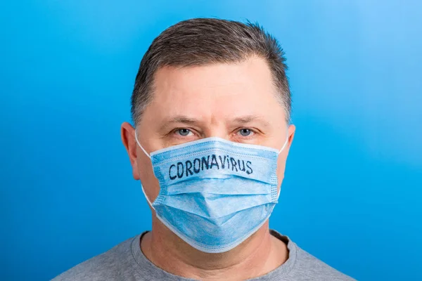 Ritratto di un malato che indossa una maschera medica con testo coronavirus su sfondo blu. Concetto di Coronavirus. Proteggi la tua salute — Foto Stock