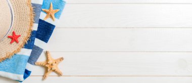 Straw hat, blue towel and starfish banner On a white wooden background. top view summer holiday concept with copy space