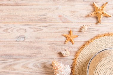 Beach hat with seashells on brown wooden table. summer backgroun