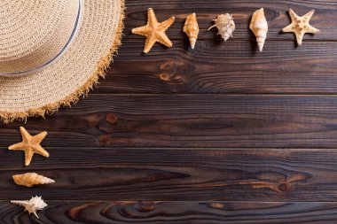 Beach hat with seashells on brown wooden table. summer backgroun