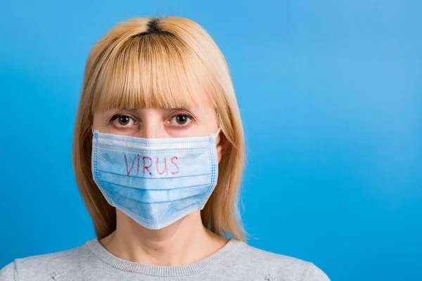 Portretul femeii purtând mască medicală cu text de virus pe fundal albastru. Conceptul de coronavirus. Protecție respiratorie — Fotografie, imagine de stoc