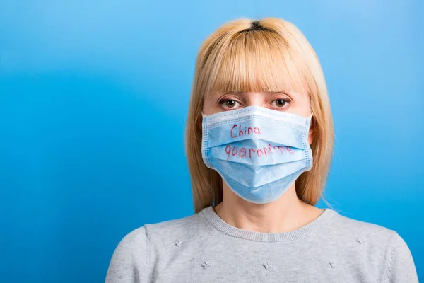 Porträtt av en kvinna som bär medicinsk mask med Kina karantän ord på blå bakgrund. Coronavirus och hälsovårdskoncept — Stockfoto