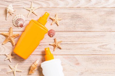 sun protection cream bottle and seashells on wooden background w