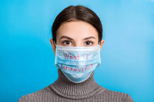 Porträtt av en kvinna som bär medicinsk mask med vad som är coronavirus ord på blå bakgrund. Coronavirus och hälsovårdskoncept — Stockfoto