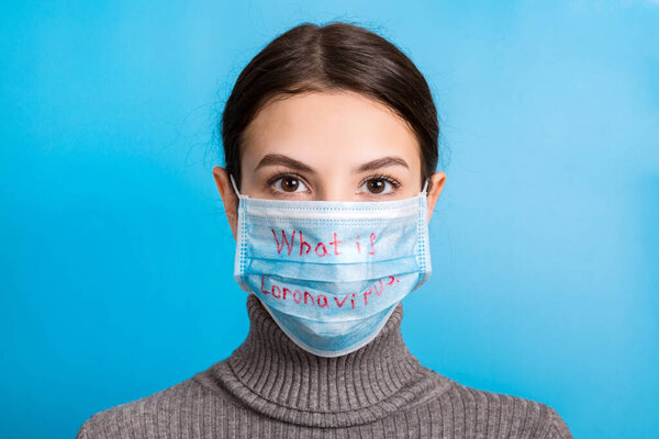 Portrait of a woman wearing medical mask with what is coronavirus word at blue background. Coronavirus and healthcare concept