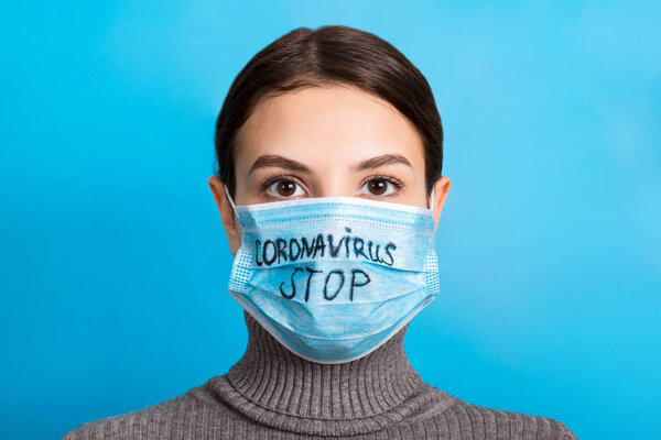 Portrait of a woman in medical mask with stop coronavirus text at blue background. Coronavirus concept. Respiratory protection
