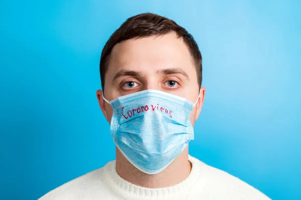 Ritratto di un malato che indossa una maschera medica con testo coronavirus su sfondo blu. Concetto di Coronavirus. Proteggi la tua salute — Foto Stock