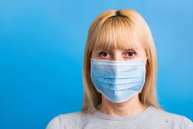 Mavi arka planda tıbbi maske takan kadın portresi. Sağlığınızı koruyun. Coronavirus konsepti