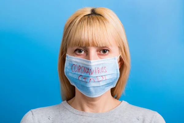 Porträtt av en kvinna i medicinsk mask med stopp coronavirus text på blå bakgrund. Coronavirus-konceptet. Andningsskydd — Stockfoto