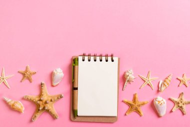 notebook with sseashells on pink background top view flat lay. P