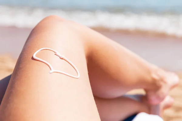 Sonnencreme in Herzform am Bein der Frau beim Sonnenbaden auf der — Stockfoto