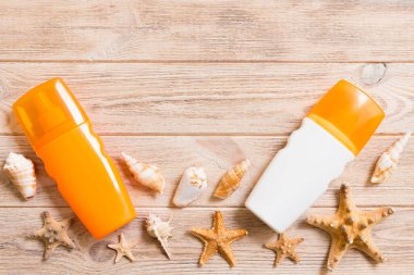 Sunscreen bottles with seashells and starfish on wooden table wi