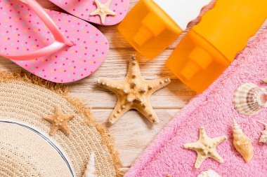 Parmak arası terlikler, hasır şapka, denizyıldızı, güneş kremi şişesi, vücut losyonu.