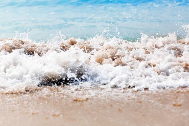 Kumlu plajda sıçramaları ile deniz dalgaları yakın. Yakın çekim