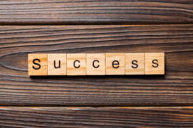 Tahta blokta yazan başarı kelimesi. Masada başarı metni, konsept