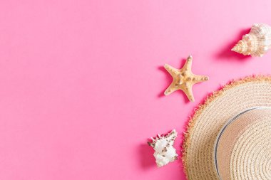 Pembe tahta masanın üzerinde deniz kabukları olan plaj şapkası. yaz arkaplanı