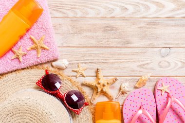 Parmak arası terlikler, hasır şapka, denizyıldızı, güneş kremi şişesi, vücut losyonu.