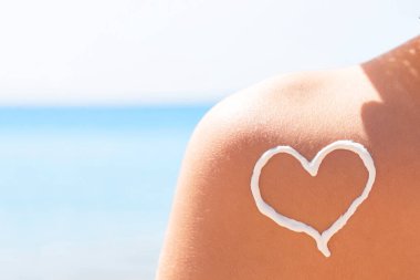 Sahilde güneş kreminden yapılmış bir kalp kadının omzuna çizilir..