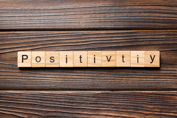 positivity word written on wood block. positivity text on wooden table for your desing, concept.