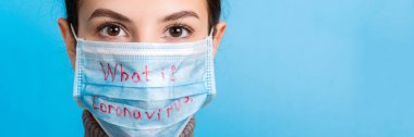 Mavi arka planda Coronavirus kelimesiyle tıbbi maske takan bir kadının portresi. Coronavirus ve sağlık konsepti.
