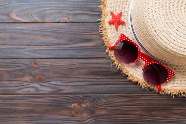 Hasır şapka, güneş gözlüğü ve deniz kabukları koyu ahşap arka plan üzerinde. kopya alanı ile üst görünüm yaz tatili konsepti.