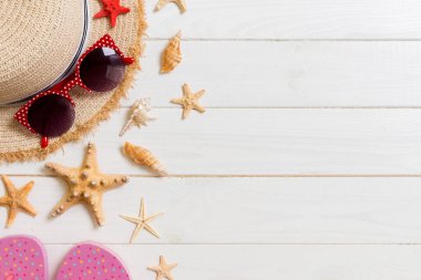 Hasır şapka, pembe parmak arası terlik, güneş gözlüğü ve denizyıldızı Beyaz ahşap arka plan üzerinde. kopya alanı ile üst görünüm yaz tatili konsepti.