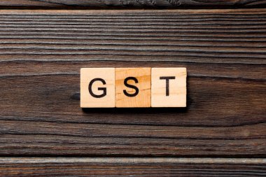 Tahta blokta GST kelimesi yazıyor. Ahşap masa üzerinde GST metin desing, konsept.