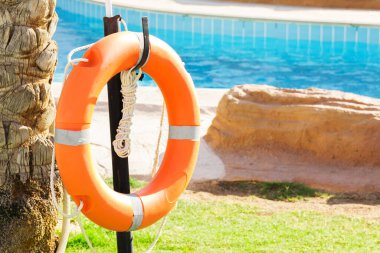 turuncu acil lifebuoy otelde tatilhavuz yakınında çit asılı.