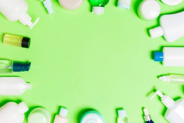 Plastik vücut bakımı şişesi çerçeve düz tasarım için yeşil arka plan boş alan kozmetik ürünleri ile kompozisyon yatıyordu. Beyaz Kozmetik Konteynerler, kopya alanı ile üst görünüm seti.