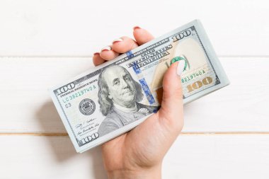 Femle elinde 100 dolarlık banknotlar. Renkli arka planda para tasarrufu konseptinin en iyi görünümü.