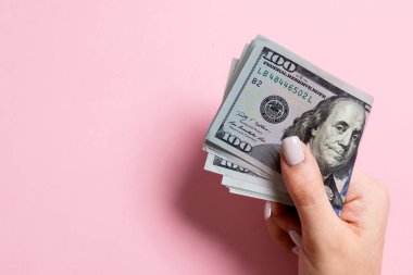 Renkli arka planda kadın elinde yüz dolarlık banknotlar bir paket. Kopya alanı ile maaş kavramı.