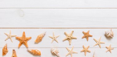 Beyaz arka plan pankartıyla deniz yıldızı ve deniz kabukları olan yaz zamanı ahşap masası. Alan arkaplanını kopyala, yaz konsepti.