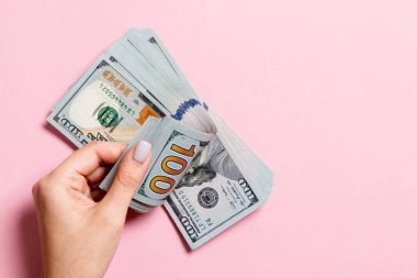 İş kadınının elleri renkli arka planda 100 dolarlık banknotları sayıyor. Maaş ve ücret kavramı. Yatırım kavramına en üst düzey bakış.