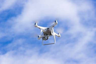 Quadcopter drone mavi gökyüzünde uçuyor. İnsansız hava aracı. Yükseklerden uzaktan çekim. Modern dijital kamera.