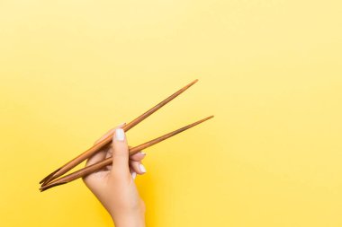 Sarı arka planda çubuklu kadın eli. Tasarımınız için emty alanı ile geleneksel Asya gıda.