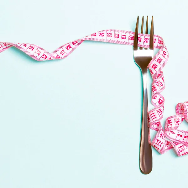 Çatal ve kıvrılmış ölçüm bandı üst görünüme sahip mavi arka plan üzerindedir. Kilo kaybı ve tasarım için alan için diyet Kavramı.