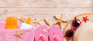 Parmak arası terlikler, hasır şapka, denizyıldızı, güneş kremi şişesi, ahşap arka plan pankartıyla vücut losyonu spreyi. düz uzanan yaz deniz aksesuarları arka plan, seyahat konsepti.