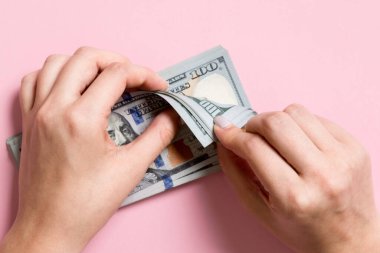 Para sayan kadın ellerinin en iyi görünümü. Renkli arka planda 100 dolarlık banknotlar. İş kavramı.