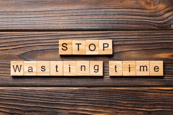 Stop wasting time word written on wood block. Stop wasting time text on wooden table for your desing, Top view concept.