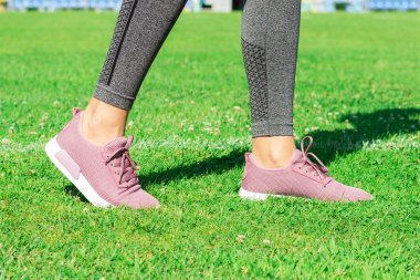 Crop image of female sporty legs and feet in running shoes at the stadium.