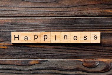 Tahta blokta yazan mutluluk kelimesi. Mutluluk metni ahşap masanın üzerinde, üst görünüm konseptiniz için..