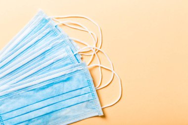 Turuncu arka plandaki koruyucu tıbbi maskelerden oluşan salgın geçmişi. Dünya karantina kavramı.