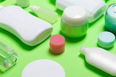 Yeşil backgound kozmetik ürünler için farklı ölçekli şişe ve kavanoz yakın çekim seti. Kopya alanı ile yüz ve vücut bakımı kavramı.