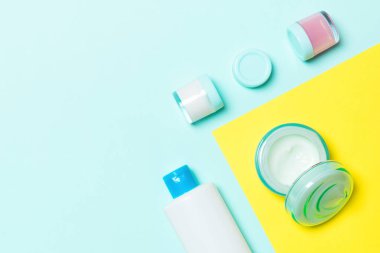 Plastik vücut bakımı şişesi grubu düz size tasarım için sarı ve mavi arka plan boş alan kozmetik ürünleri ile kompozisyon yatıyordu. Beyaz Kozmetik Konteynerler, kopya alanı ile üst görünüm seti.