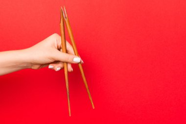 Kırmızı arka plan üzerinde kadın elleri ile tuttu ahşap çubuklar. Boş alan ile yeme kavramları için hazır.