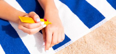 Kadın elleri güneş kremi şişesinden güneş kremi sürüyor..